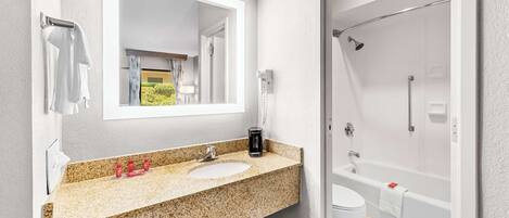 Un bagno con un piano in granito, due lavabi, uno specchio grande, una doccia e un water.