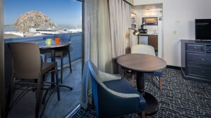 A hotel room with a balcony, a dining area, a TV, and a kitchenette. - Blue Sail Inn (Morro Bay)