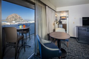 Habitación de hotel con balcón, zona de comedor, televisión y kitchenette.