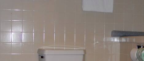 A bathroom with a toilet, a towel rack, and a toilet paper holder.