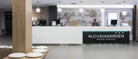 A reception area with a modern design, featuring a reception desk, a wooden column, and a seating area with round stools.