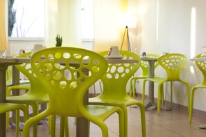 A dining area with bright green chairs and tables, a small plant, and a lamp. - Villa Bellagio Montpellier (Montpellier)