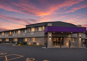 A hotel with a stone facade, multiple windows, and a parking lot with handicapped accessibility.
