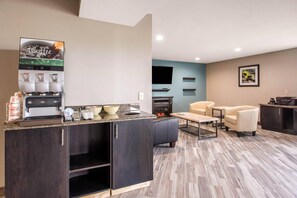 A modern kitchen with a coffee machine, a dining area with a table and chairs, and a flat-screen TV mounted on the wall.