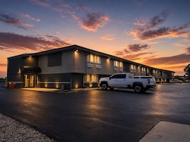 A modern building with a parking lot and a white pickup truck parked in front.