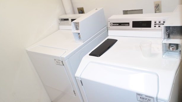 A laundry area with two white washing machines and a control panel.