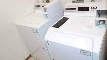 A laundry area with two white washing machines and a control panel.