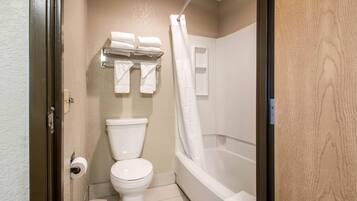 A bathroom with a toilet, a shower with a curtain, and a towel rack with multiple towels.
