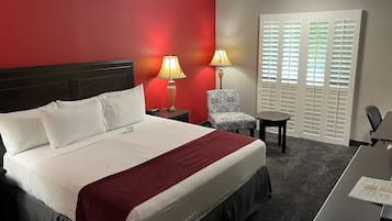Une chambre d’hôtel comprenant un lit, deux lampes de chevet, une chaise, une petite table et un bureau avec une chaise.