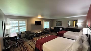 Habitación de hotel con dos camas, un escritorio, una silla, un sofá y un televisor.