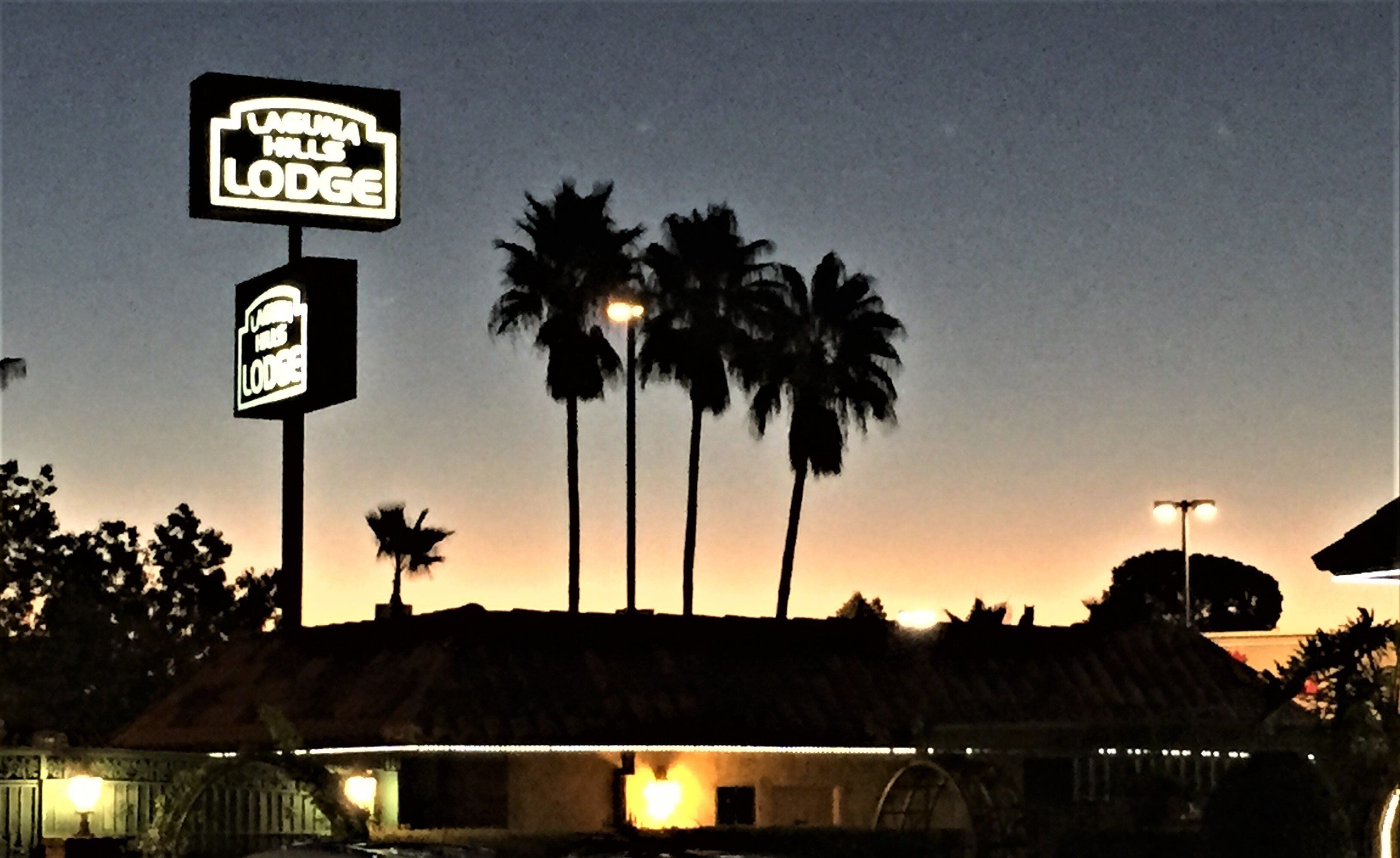A building with a sign that reads "Viva Hills Lodge" and palm trees in the background.
