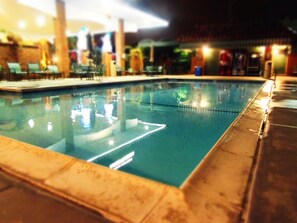 Een buitenzwembad, parasols bij het zwembad en ligstoelen