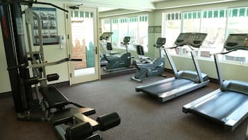 Un gimnasio con cintas de correr, máquinas de pesas y una tabla de ejercicios.