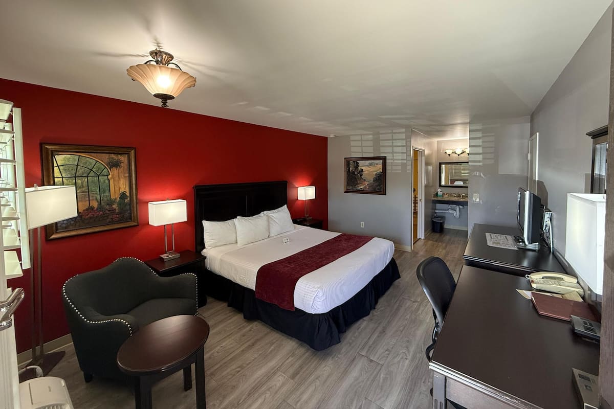 Ein Hotelzimmer mit Bett, Schreibtisch, Stuhl und Deckenventilator.