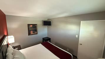Une chambre d’hôtel avec un lit, un bureau, une chaise, une télévision et une porte.