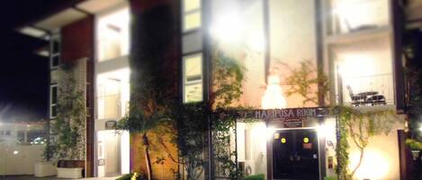 A building with a sign reading "MARIPOSA ROOM" at the entrance, surrounded by potted plants and a well-lit facade.