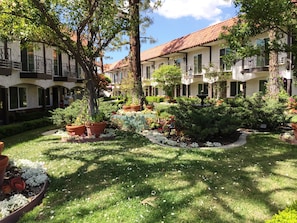 Un patio central con una fuente, rodeado de plantas en macetas y un césped bien cuidado.