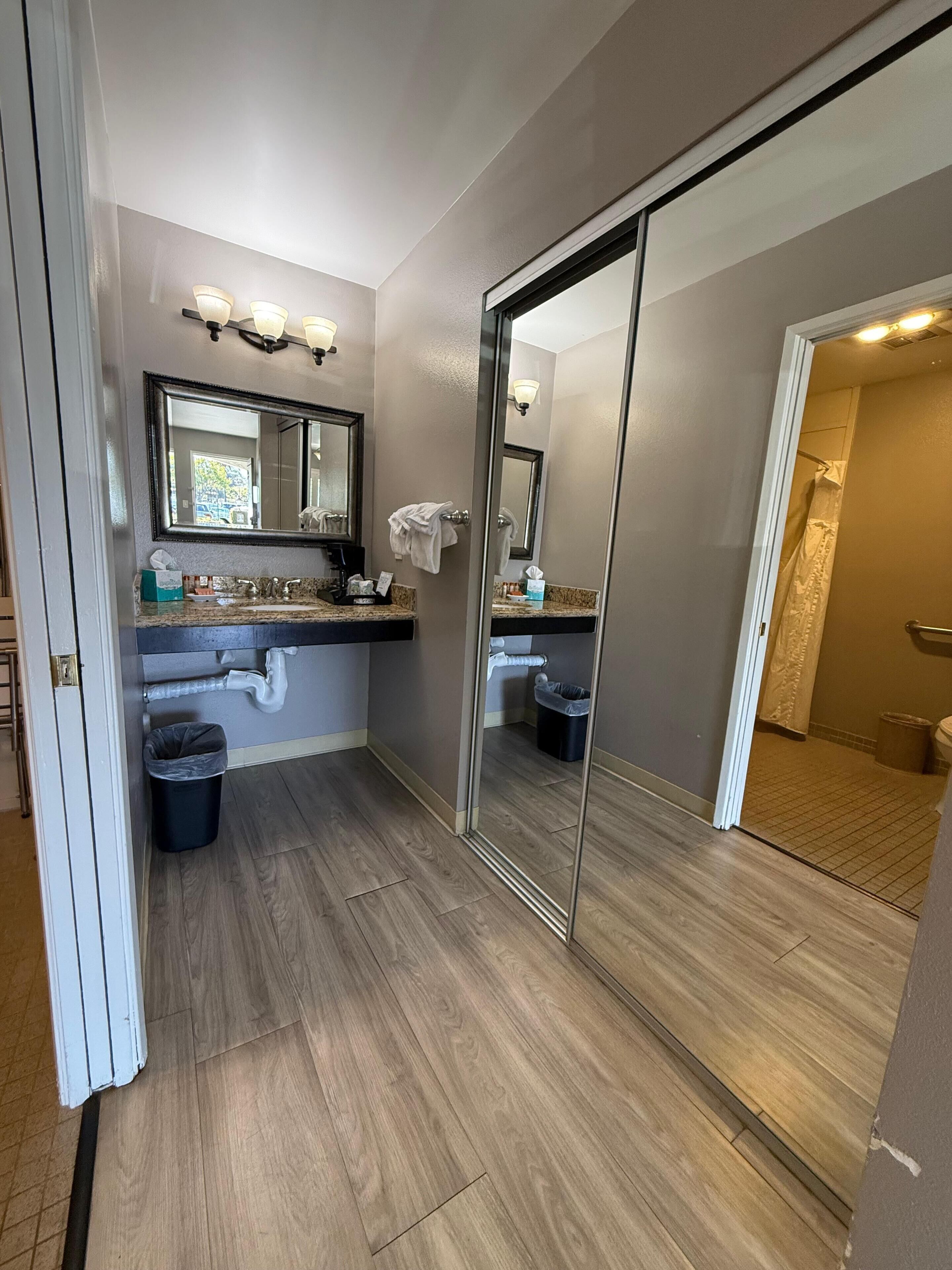 A modern bathroom with a large mirror, a vanity with a sink, and a shower area.