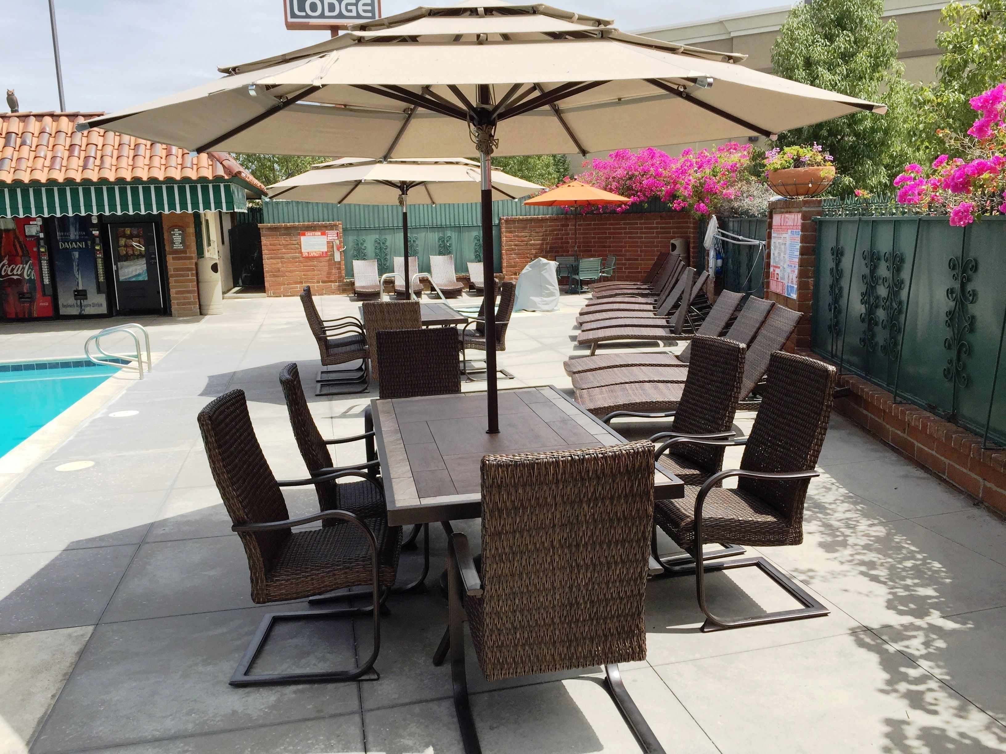 A poolside area with lounge chairs and umbrellas, a pool, and a sign indicating a lodge.