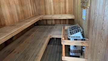 Una sauna con paredes y bancos de madera, un calentador de metal y un letrero que dice 'No Water Please'.