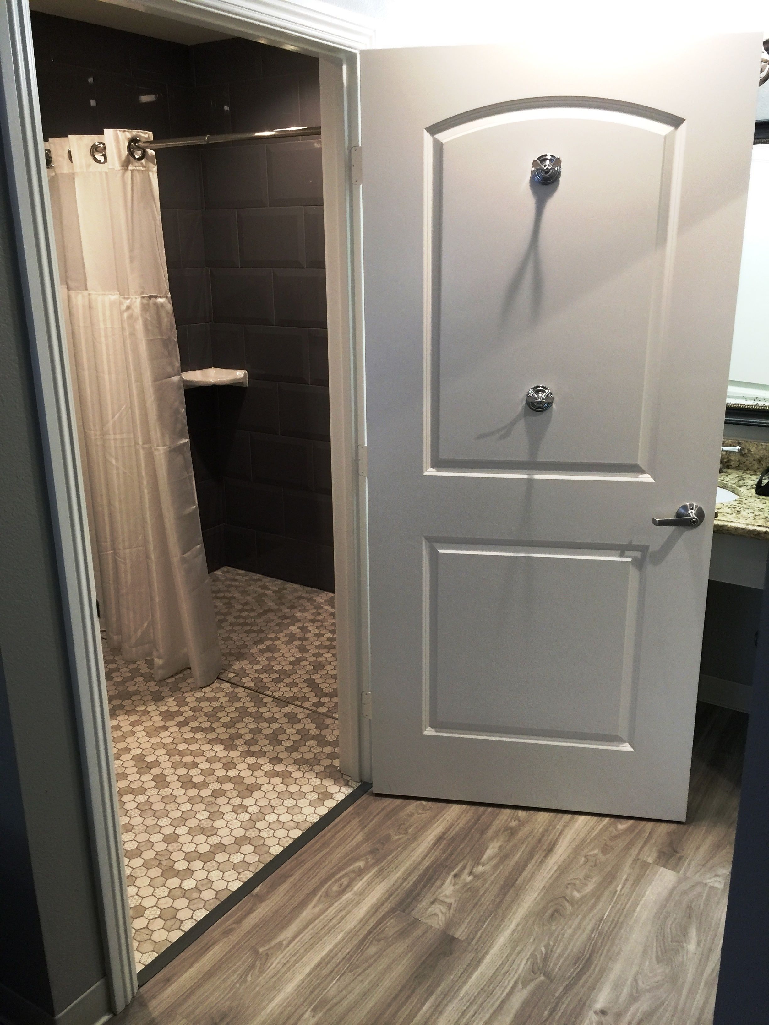 Une salle de bain avec une douche, des toilettes et une porte dotée d’une poignée.