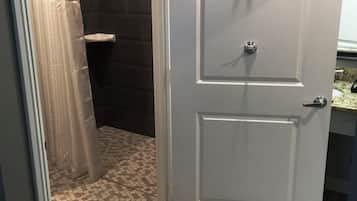 Une salle de bain avec une douche, des toilettes et une porte dotée d’une poignée.