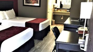 A hotel room with two beds, a desk, a chair, a mirror, and a picture on the wall.