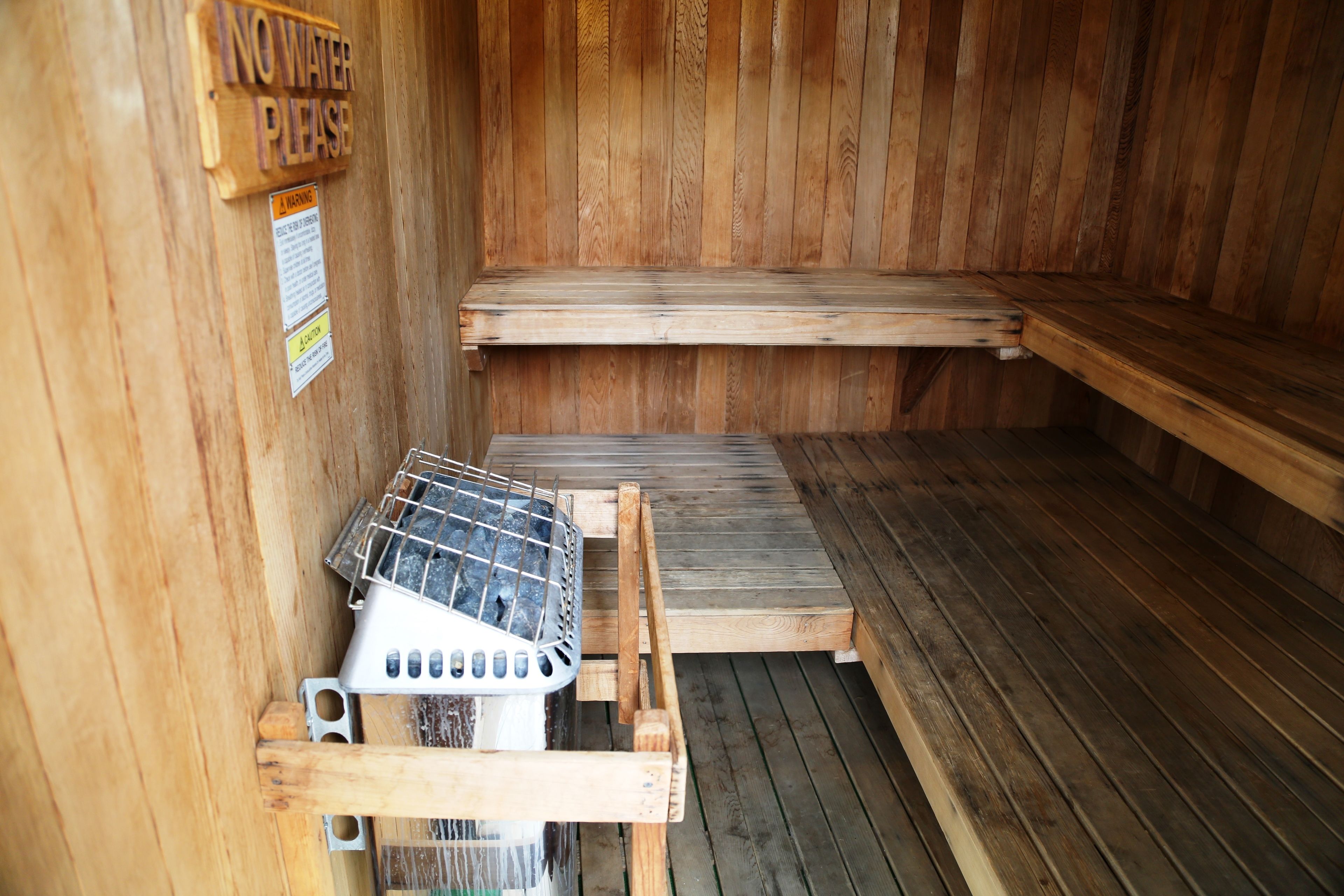 Eine Sauna mit Holzbänken und einem Metallkorb.