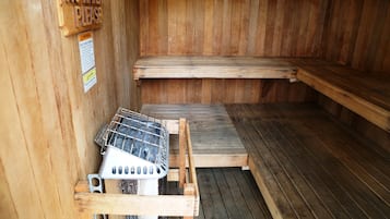 Una sauna con bancos de madera y una parrilla de metal.