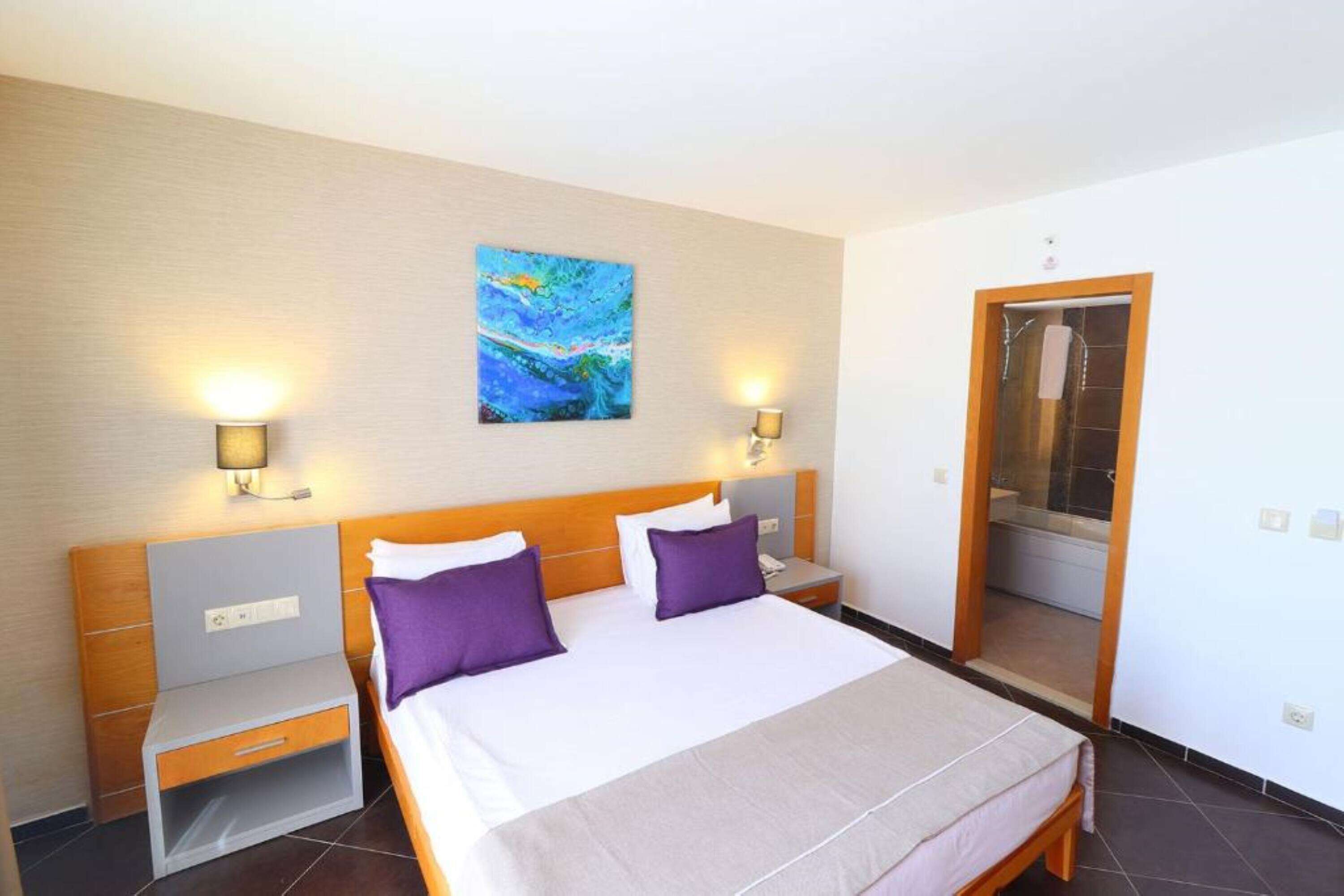 Hotelkamer met een bed, twee nachtkastjes, een schilderij aan de muur en een deur naar de badkamer.