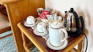 A wooden side table with a tea set, a kettle, and a vase of yellow flowers. - Rathbaun Hotel (Lisdoonvarna)
