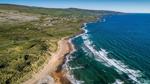 An aerial view of a coastal area with a beach, clear blue sea, and green hills. - Rathbaun Hotel (Lisdoonvarna)