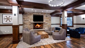 A living room with a stone fireplace, leather sofas, and a wooden coffee table. - The Village at Empire - by Deer Valley (Park City)