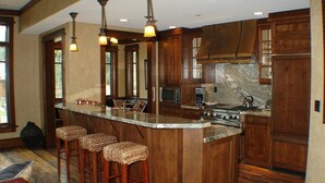 A kitchen with a large island, wooden cabinets, and bar stools. - The Village at Empire - by Deer Valley (Park City)