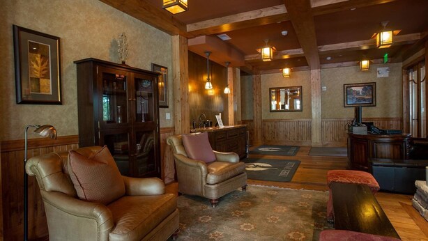 A cozy lobby with leather sofas, a wooden reception desk, and pendant lighting. - The Village at Empire - by Deer Valley (Park City)