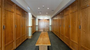 A hallway with wooden lockers, a central bench, and a door at the end. - The Village at Empire - by Deer Valley (Park City)