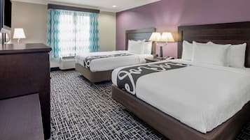 A hotel room with two beds, a desk, and a TV.