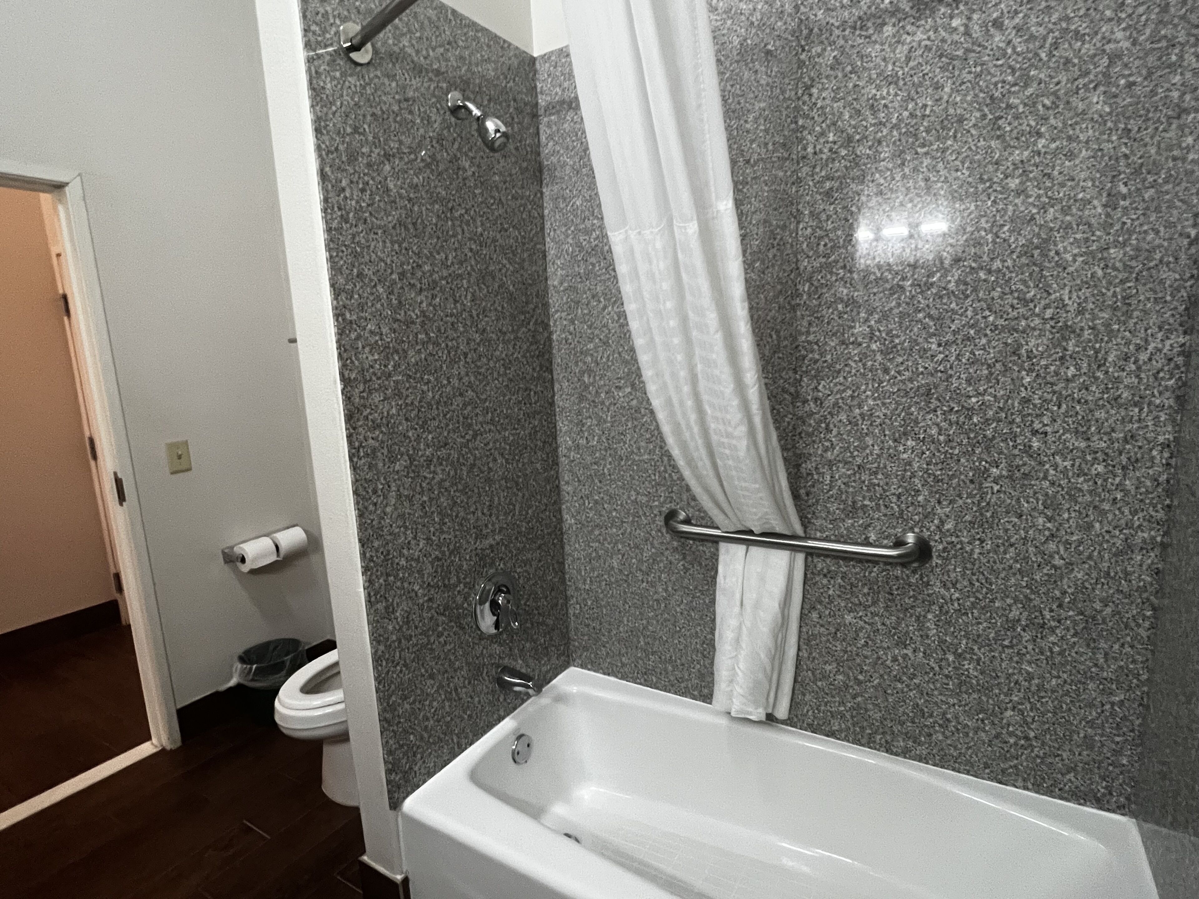 Un baño con bañera, ducha con puerta de vidrio y retrete.