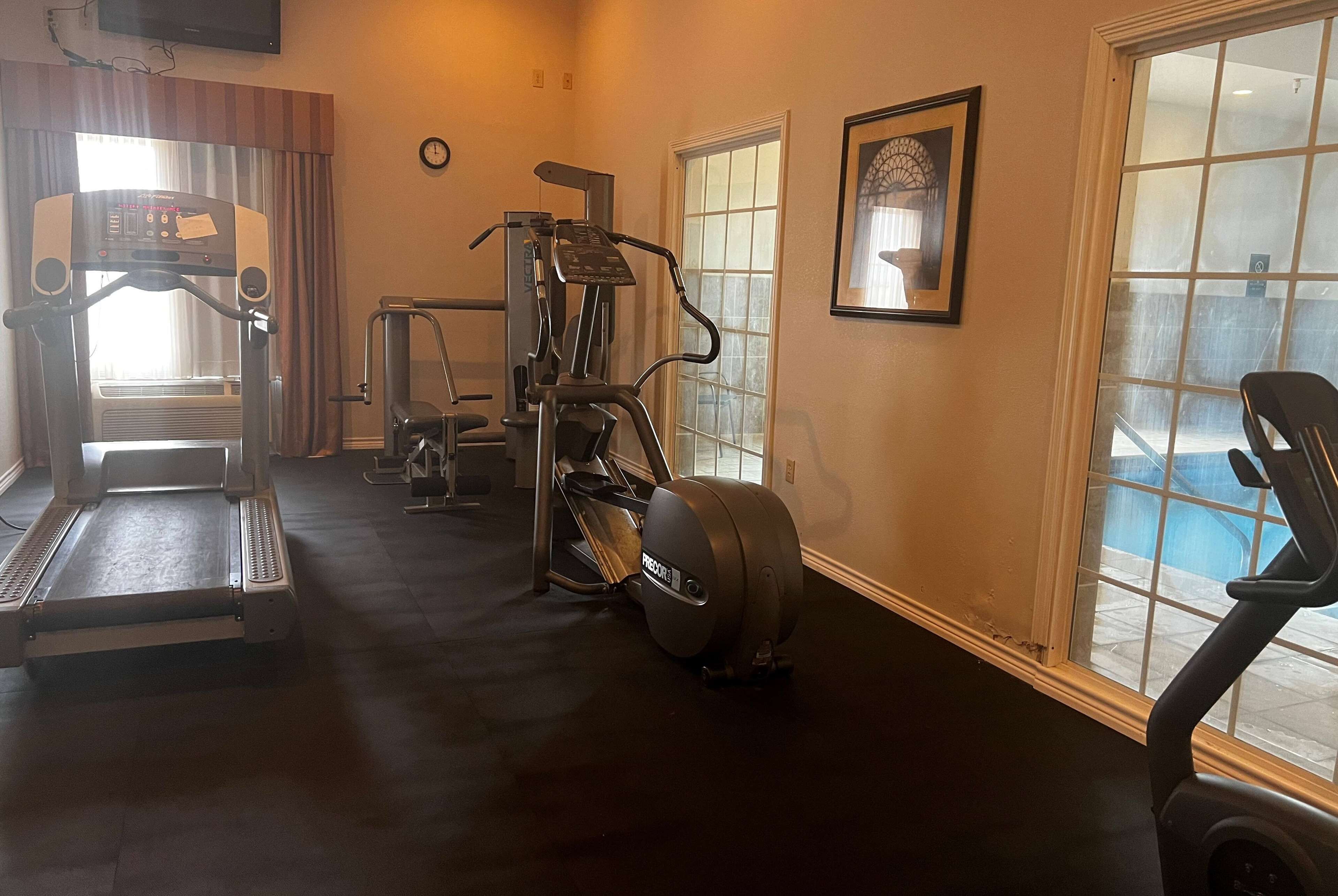 Une salle de sport équipée de tapis de course, de vélos elliptiques et de matériel de musculation.