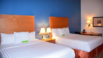 A hotel room with two beds, a desk, and a chair.