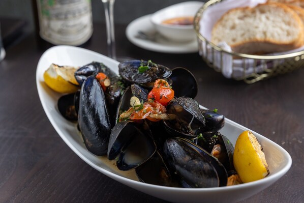 A plate of mussels with lemon and tomato garnish.