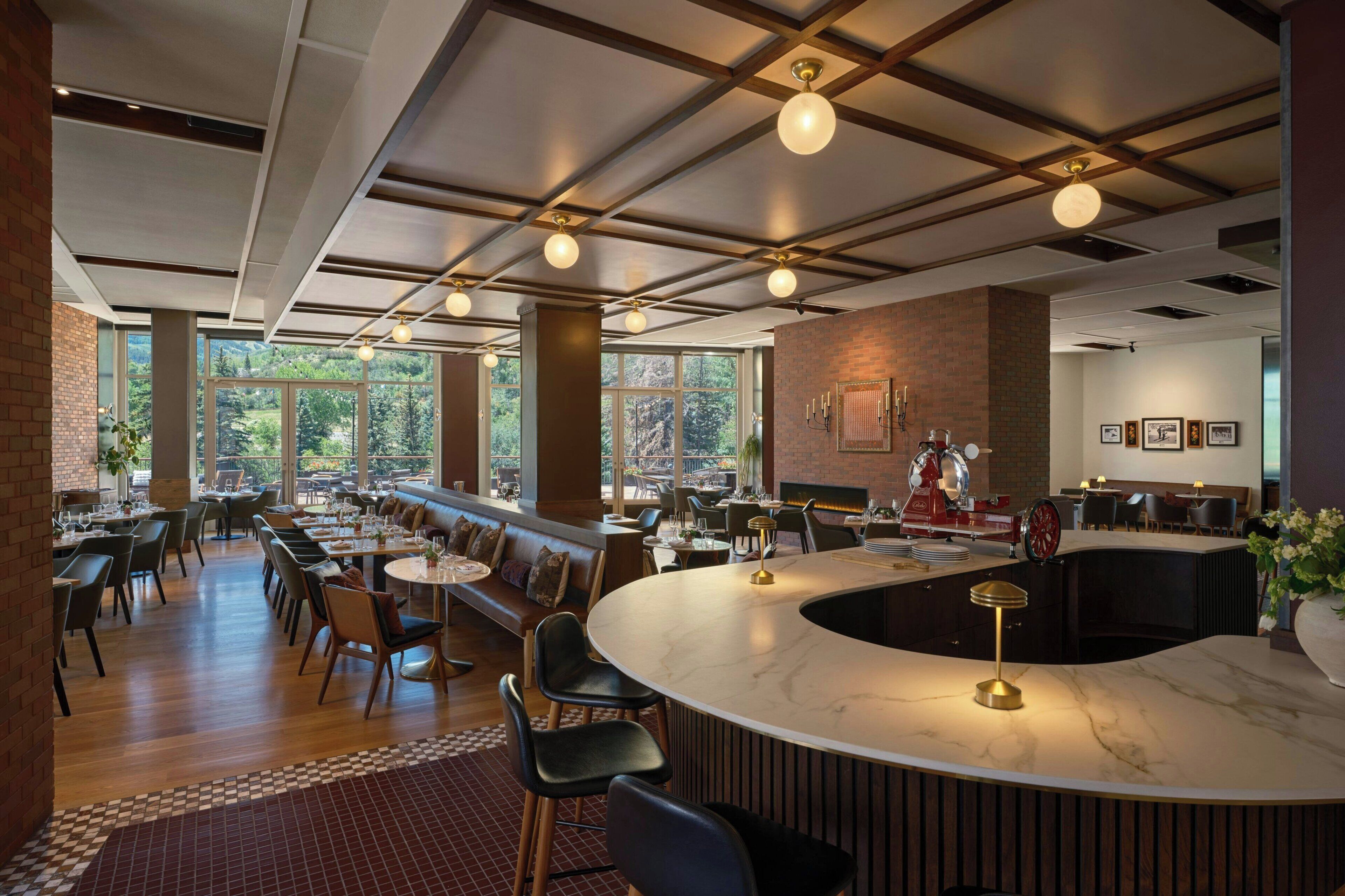 A restaurant with a bar area, seating, and a view of the outdoors.