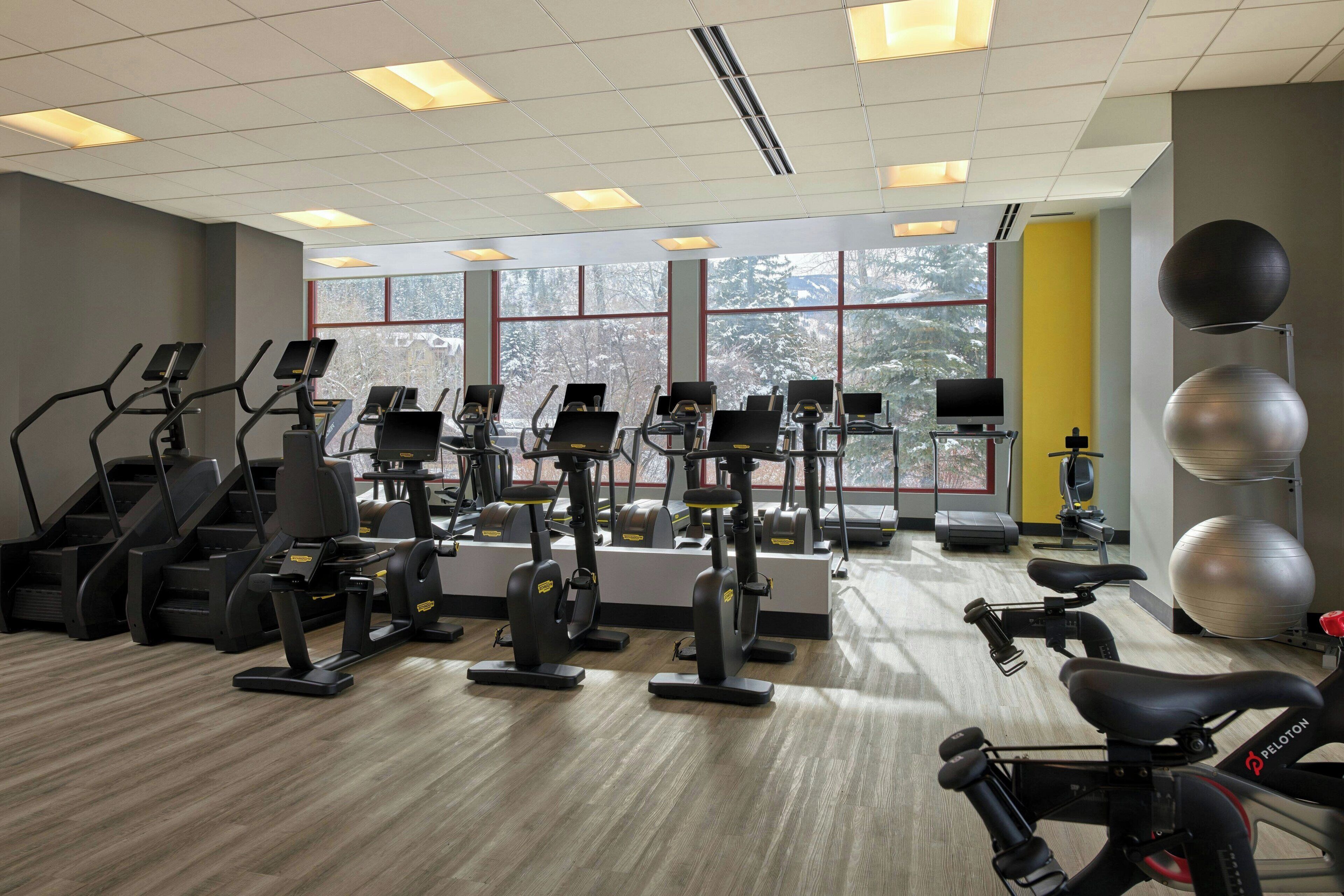Un gimnasio con cintas de correr, elípticas y pelotas de ejercicio.