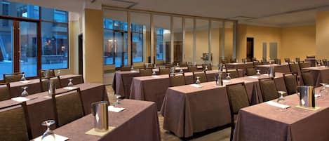 A conference room with multiple tables, chairs, and large windows.