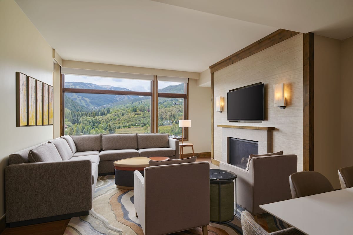 A modern living room with a large sectional sofa, a dining table, and a fireplace.