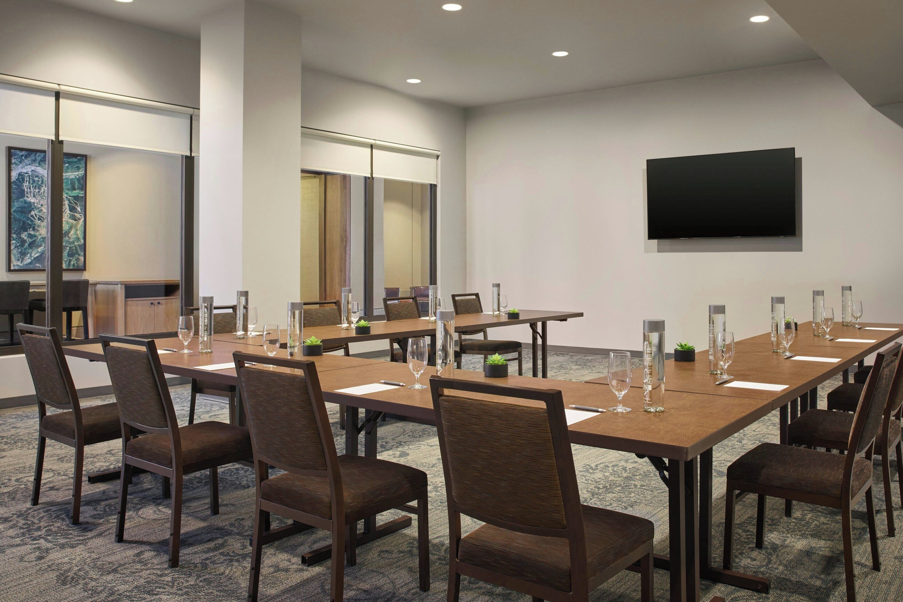 A conference room with a long table, chairs, and a flat-screen TV on the wall.