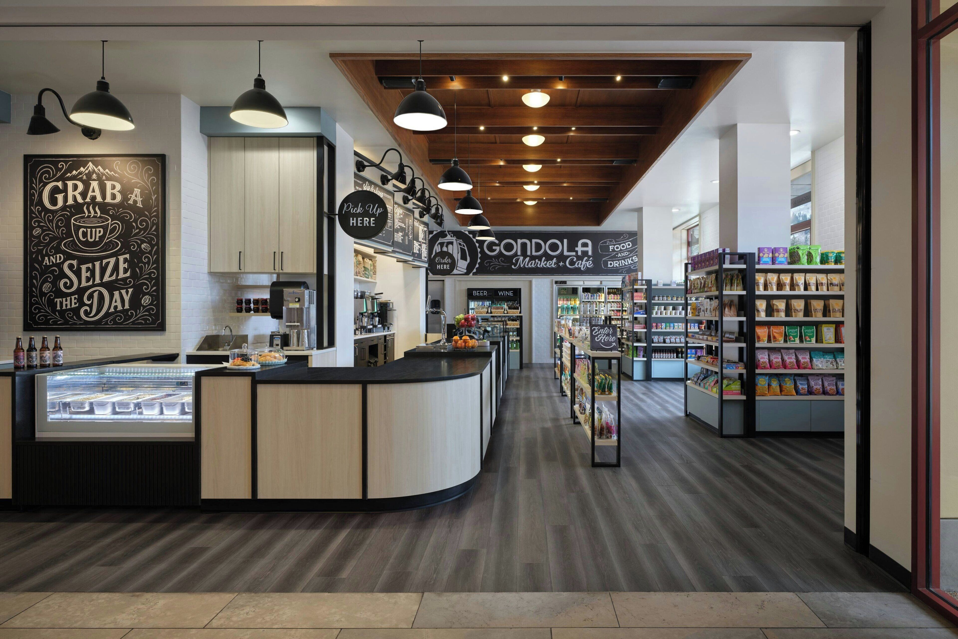 Un café moderne avec un comptoir central, des luminaires suspendus et une grande variété de plats et de boissons au menu.