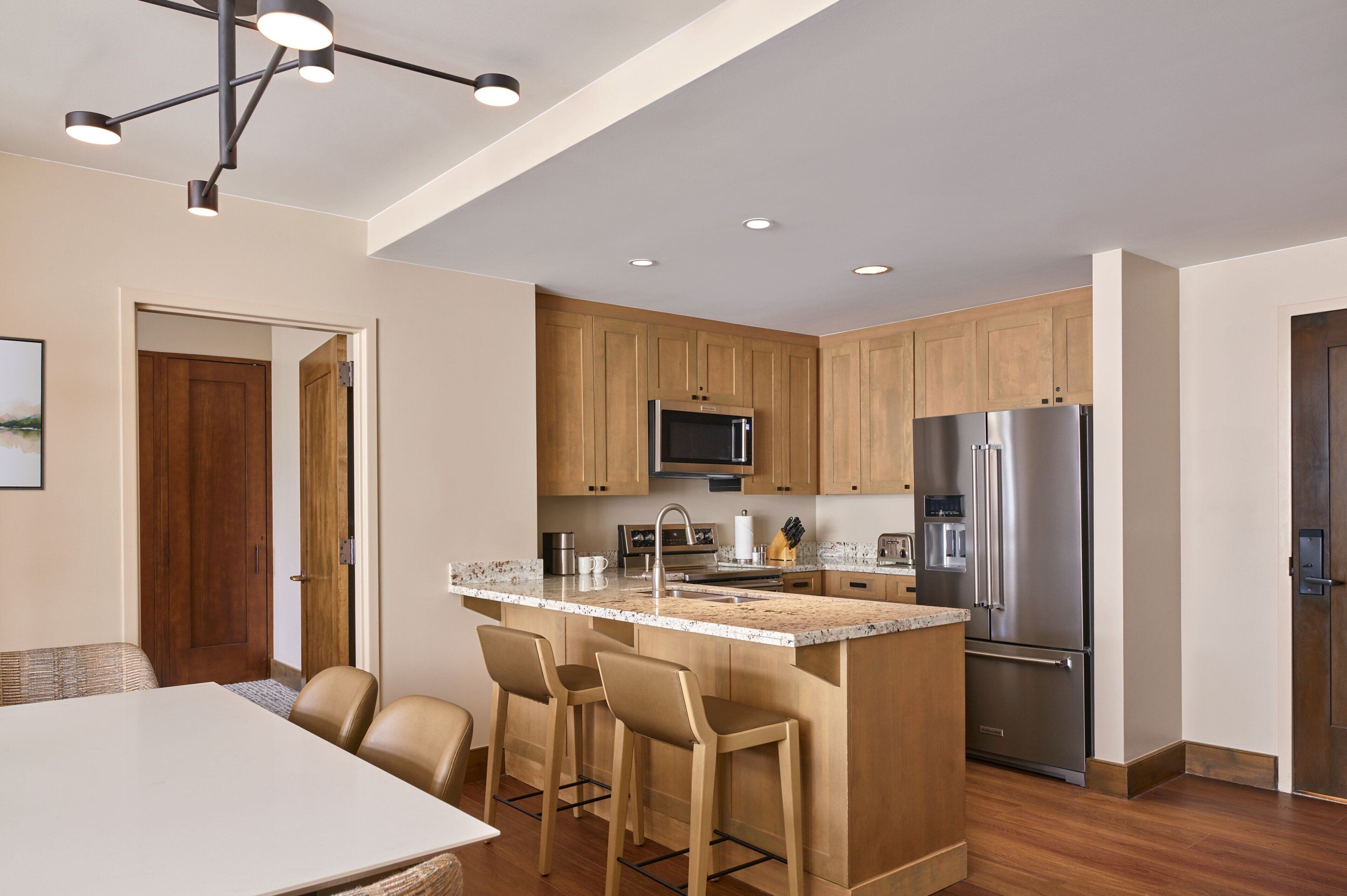 A modern kitchen with wooden cabinets, stainless steel appliances, and a central island with bar stools.