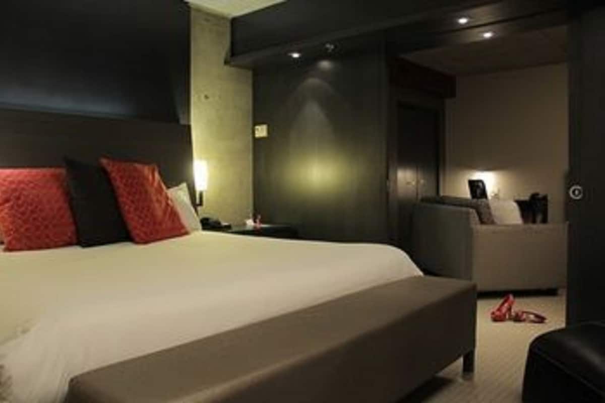 A modern hotel room with a large bed, a seating area, and a small table.