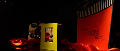 A display with a red 'Grand Times Hotel' sign, a yellow card with a wine glass image, and red fabric.